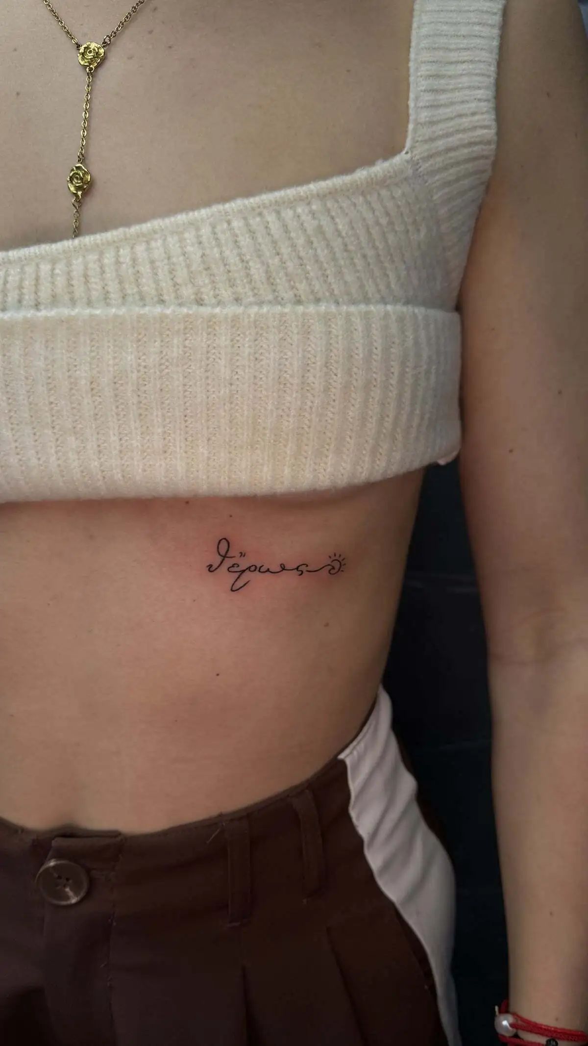 small greek word script rib tattoo