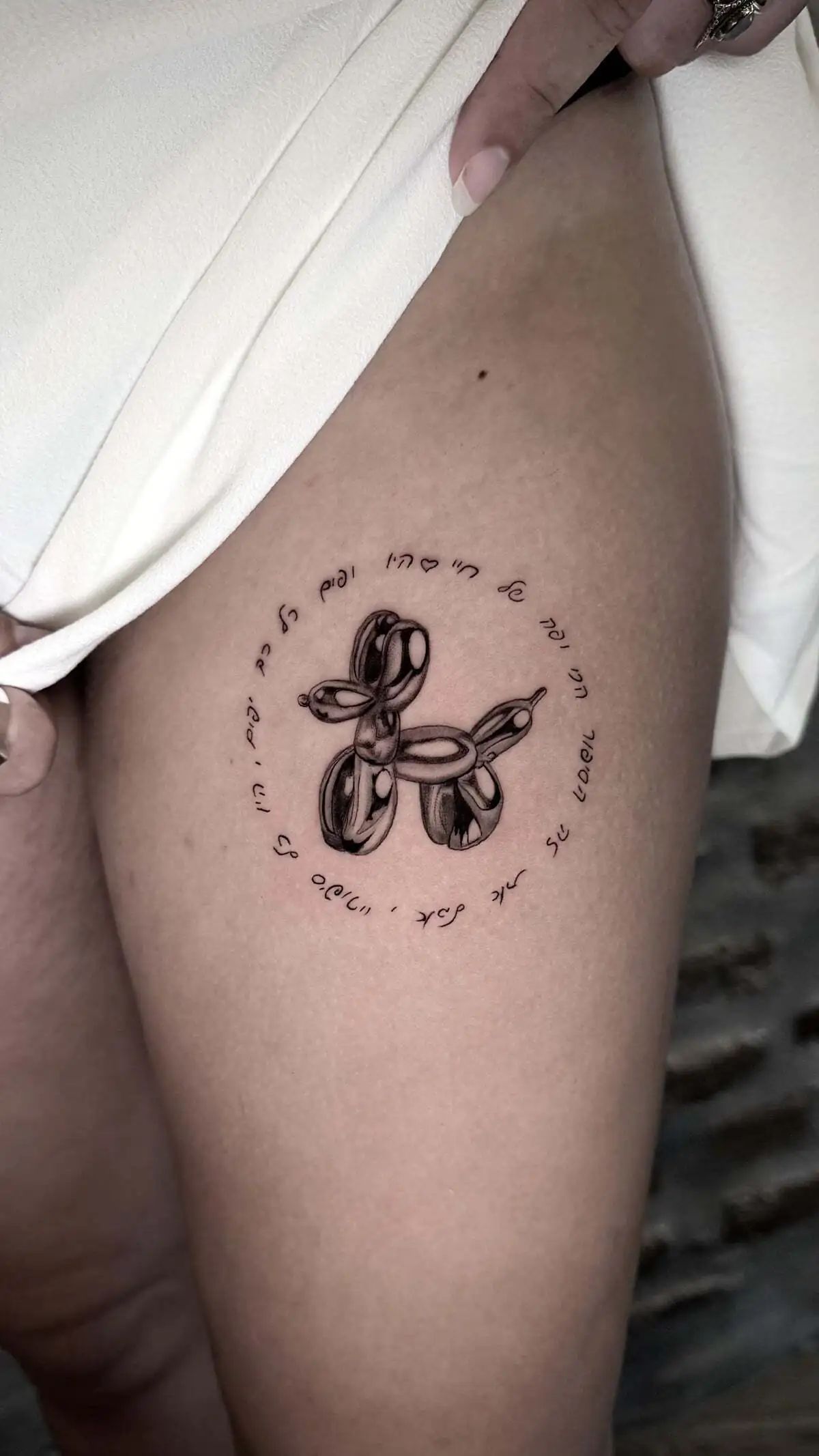 balloon dog circular script micro realism thigh tattoo