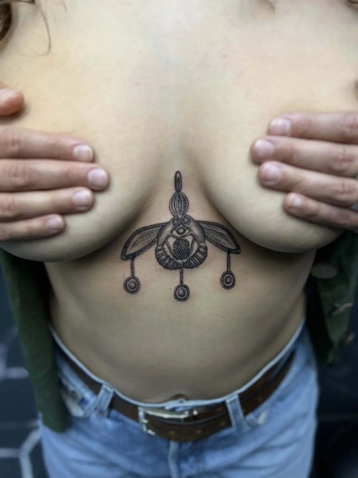 ornamental chest pendant under breast tattoo