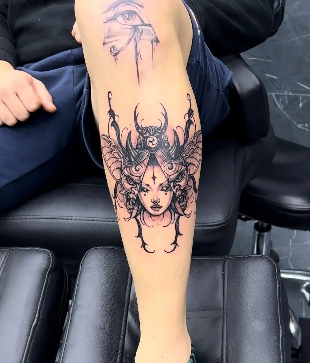 ornamental demon woman face calf tattoo